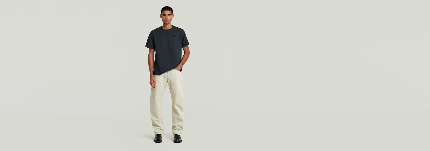 Modelo usando camiseta y pantalones claros, destacando el estilo moderno y cómodo.