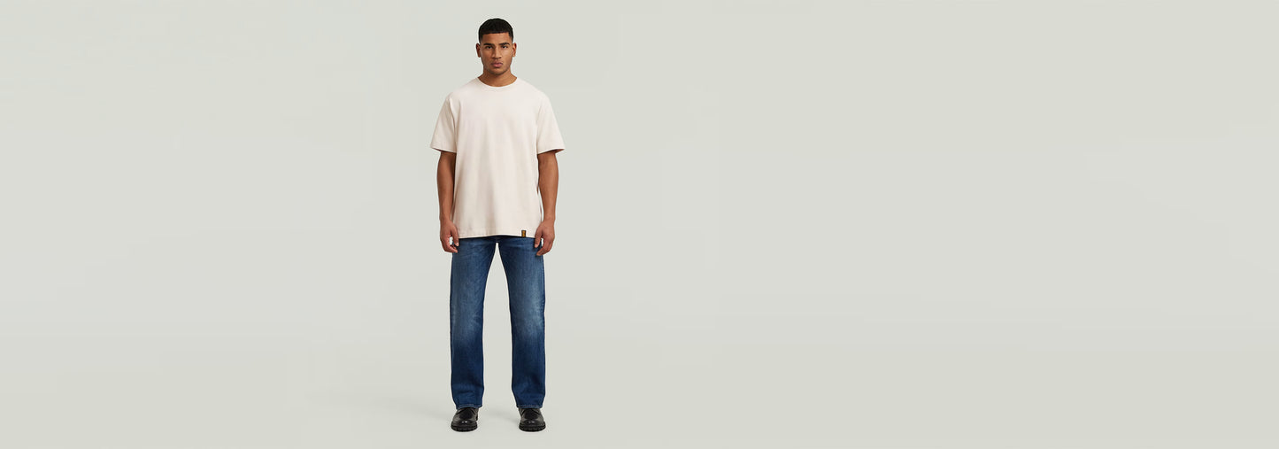 Hombre usando Jeans Dakota Regular Straight con camiseta, posando en un fondo claro.
