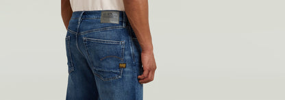 Hombre usando Jeans Dakota Regular Straight, mostrando detalles de bolsillos y etiqueta en la parte trasera.