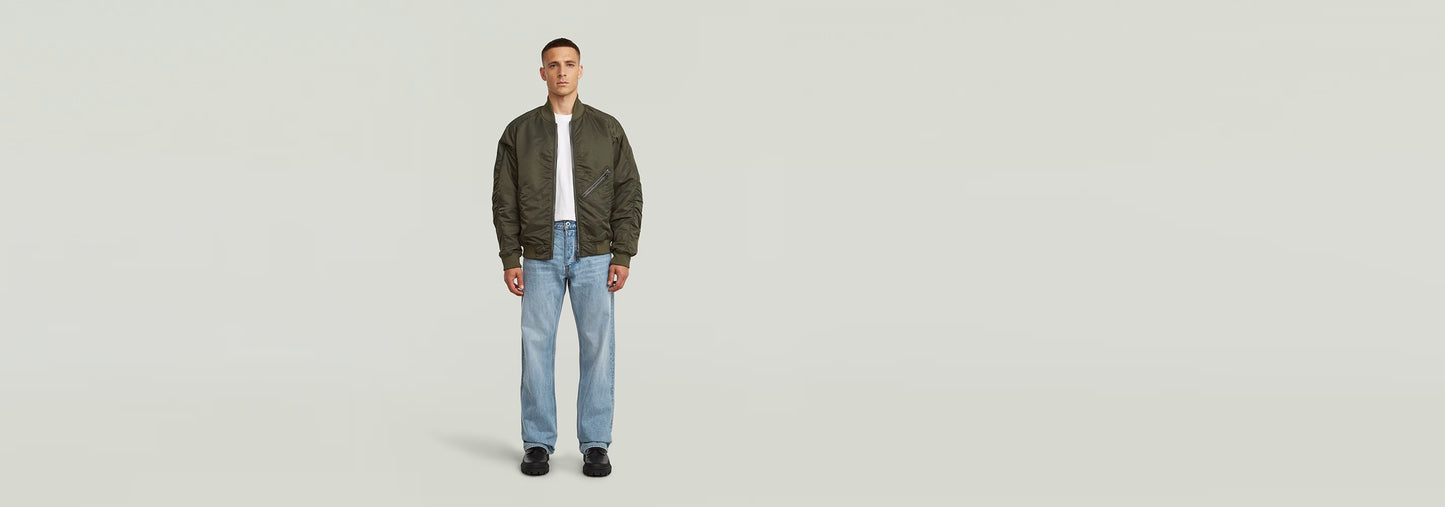 Modelo vistiendo Jeans Deeggie Relaxed Straight con chaqueta y camiseta, fondo neutro.