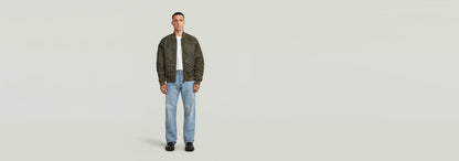 Modelo vistiendo Jeans Deeggie Relaxed Straight con chaqueta y camiseta, fondo neutro.