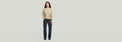 Mujer luciendo jeans G-Straight con suéter beige, fondo minimalista.