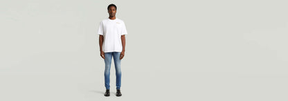 Hombre usando Jeans Revend FWD Skinny con camiseta blanca, en un fondo neutral, mostrando el corte pitillo.