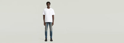 Hombre usando Jeans Revend FWD Skinny con camiseta blanca frente a fondo claro.