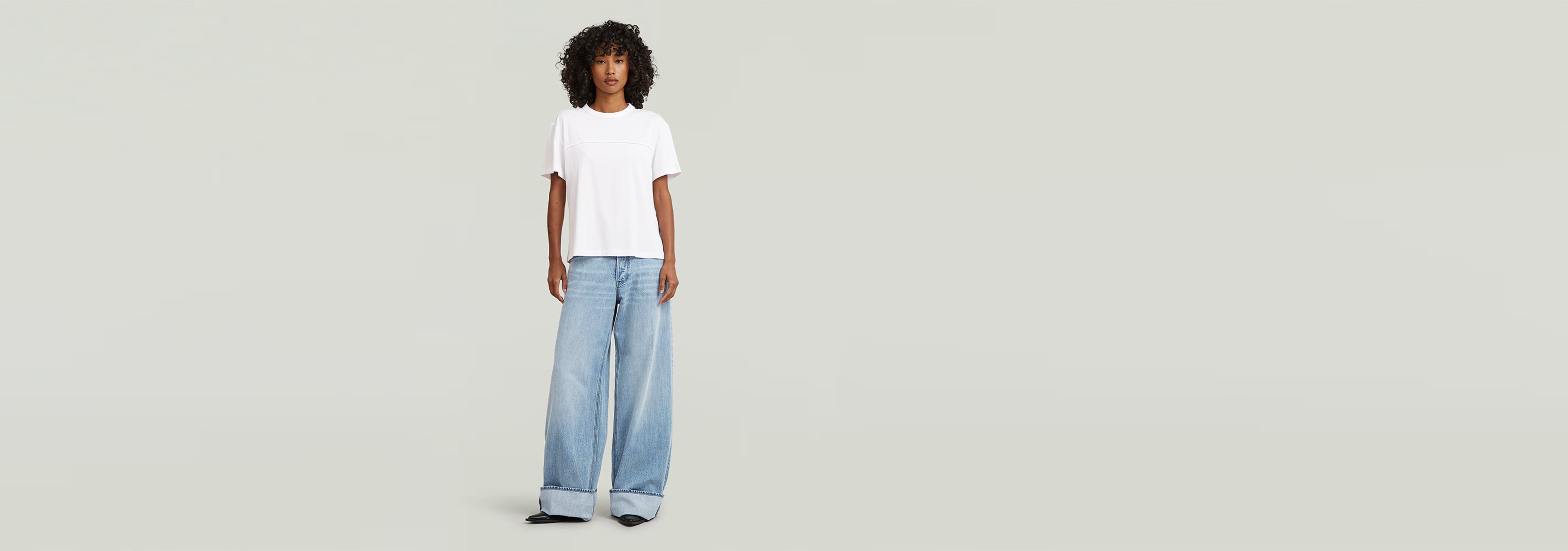 Modelo usando Jeans Roxx Wide de corte holgado con camiseta blanca sobre fondo gris.