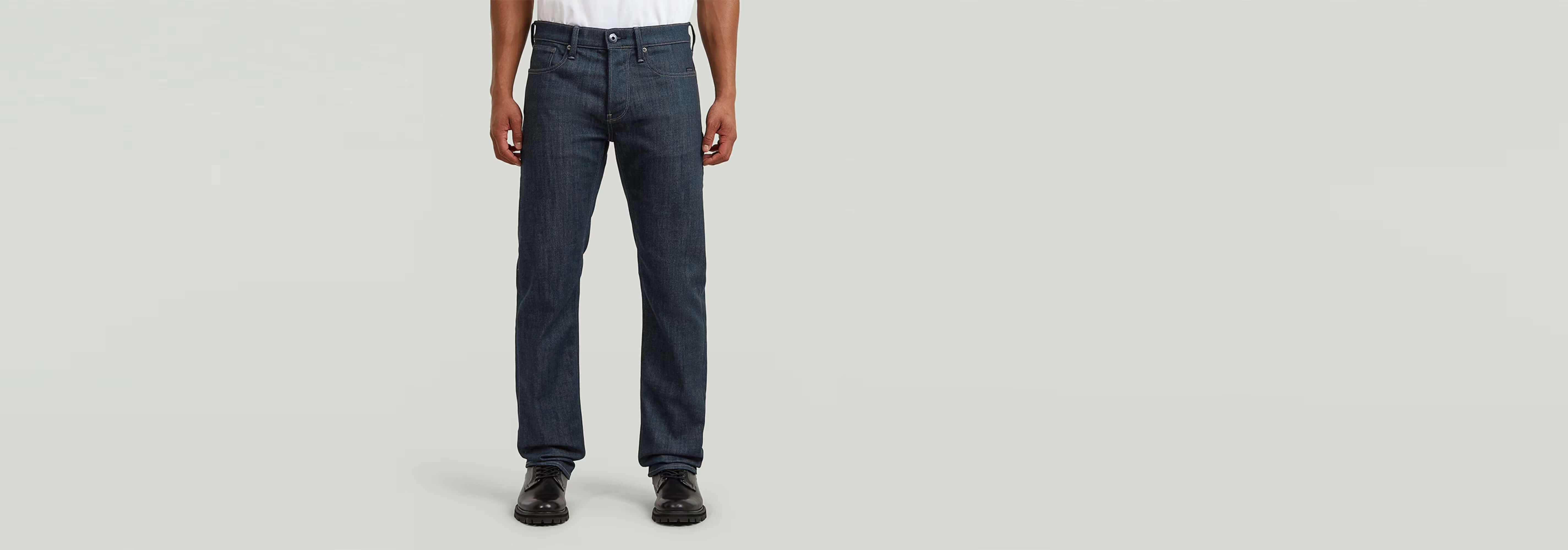 Jeans Streem Slim Tapered mostrando un corte recto ajustado en un modelo masculino con fondo gris.