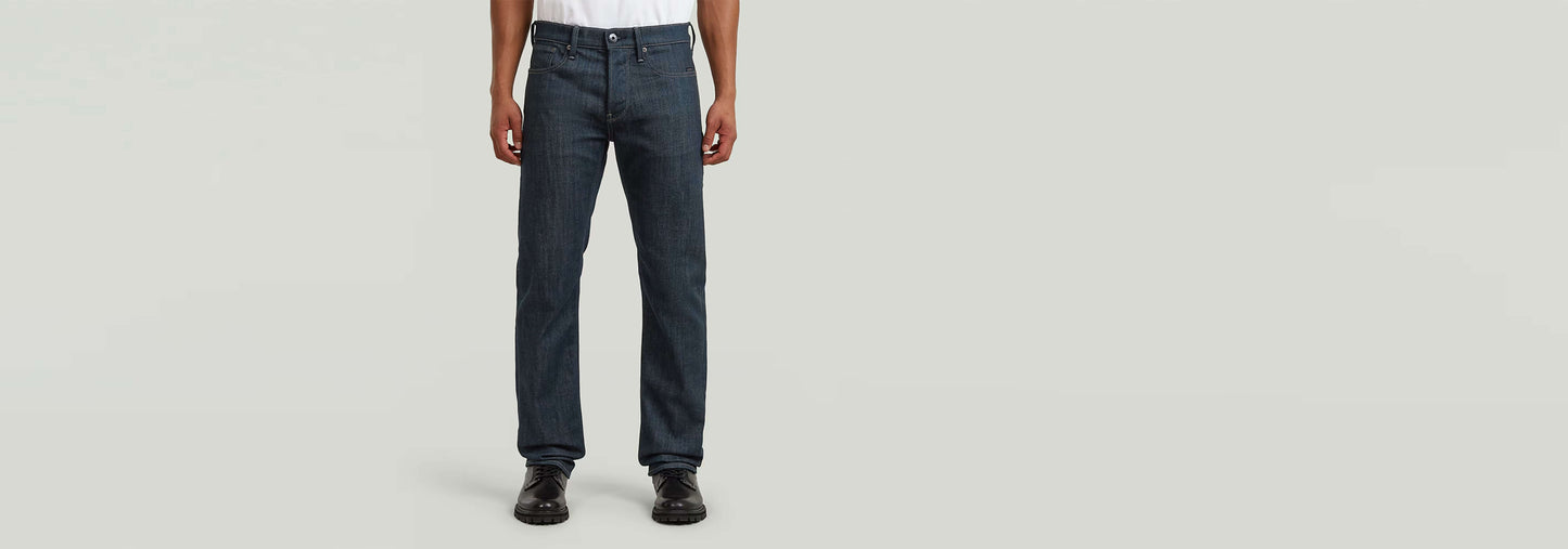 Jeans Streem Slim Tapered mostrando un corte recto ajustado en un modelo masculino con fondo gris.