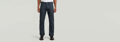 Jeans Streem Slim Tapered mostrando un corte recto ajustado en un modelo masculino con fondo gris.