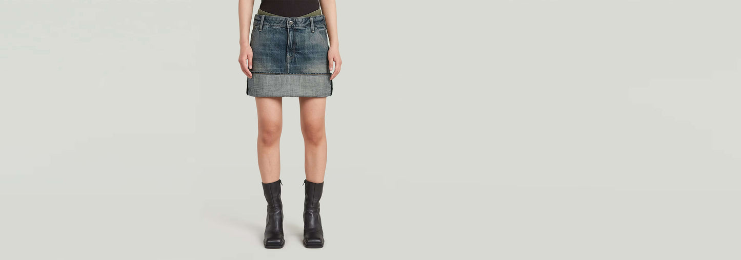 Minifalda con bajo vuelto y paneles, diseño moderno en denim greencast con patrón de bloques de color.