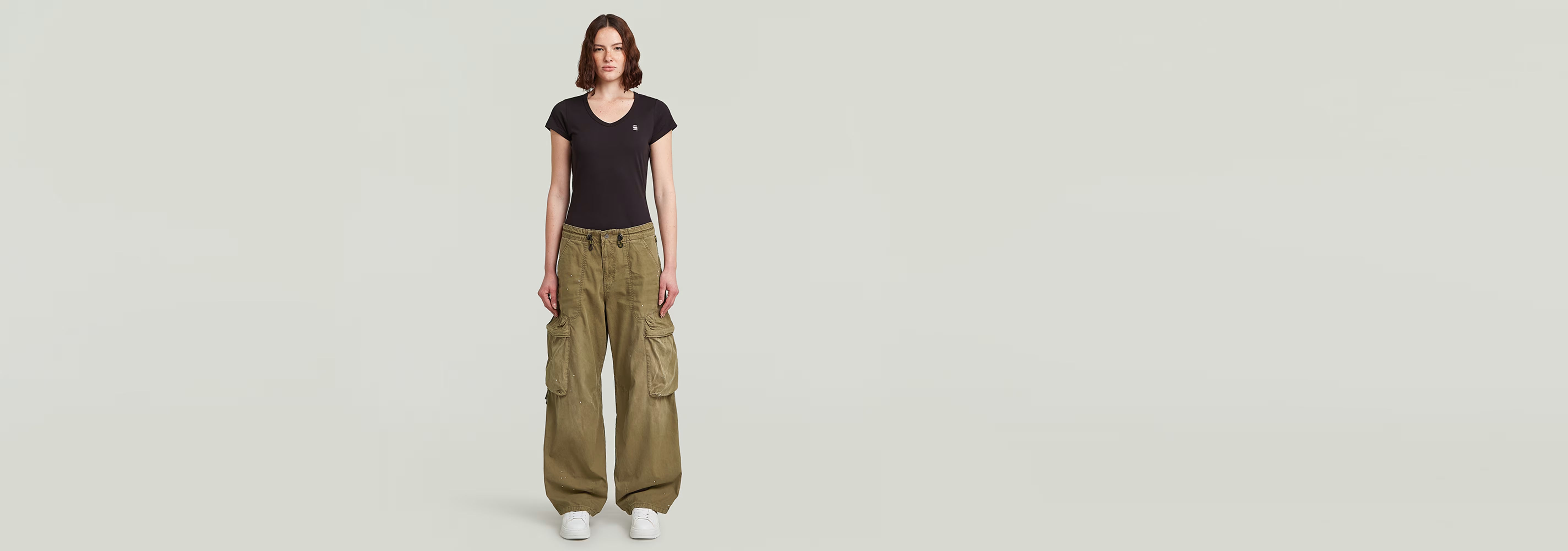 Modelo usando Pantalones Balloon Cargo de corte cónico en color verde con camiseta negra de fondo blanco.