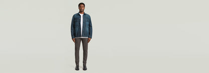 Modelo usando Pantalones Bronson 3.0 Slim Chino con chaqueta denim, fondo claro, estilo casual.