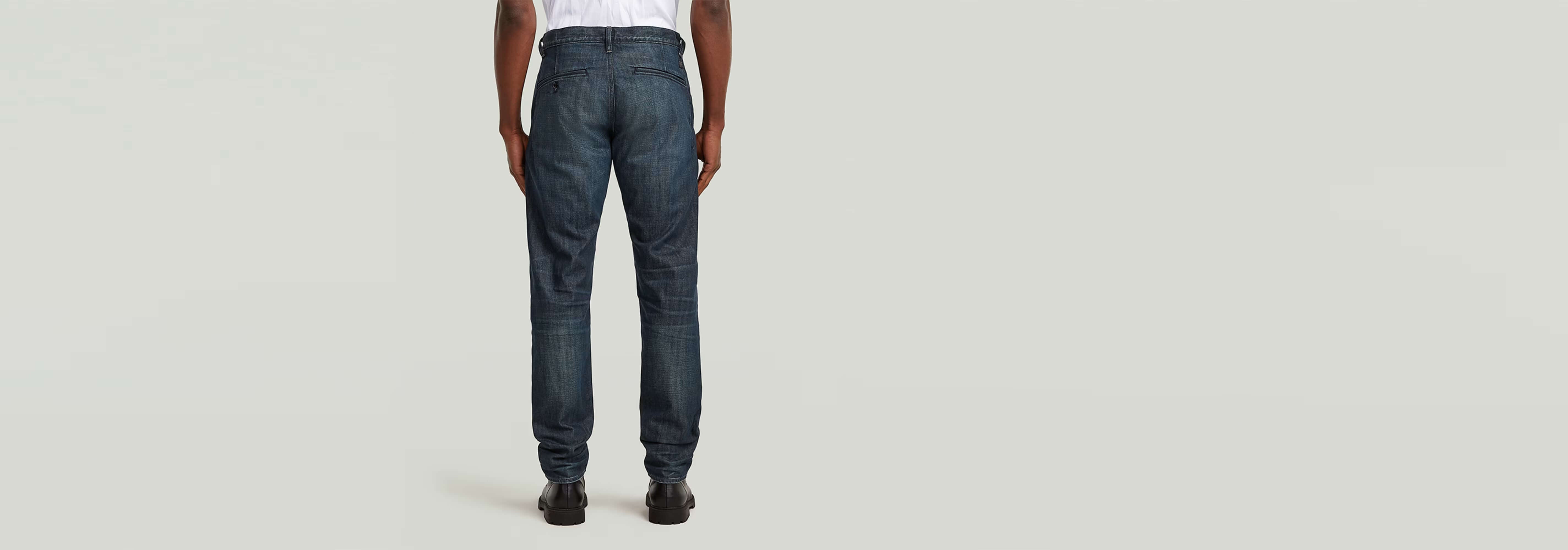 Vista trasera de los pantalones chinos Morry Tapered en denim greencast con tinte índigo.