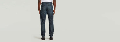 Vista trasera de los pantalones chinos Morry Tapered en denim greencast con tinte índigo.