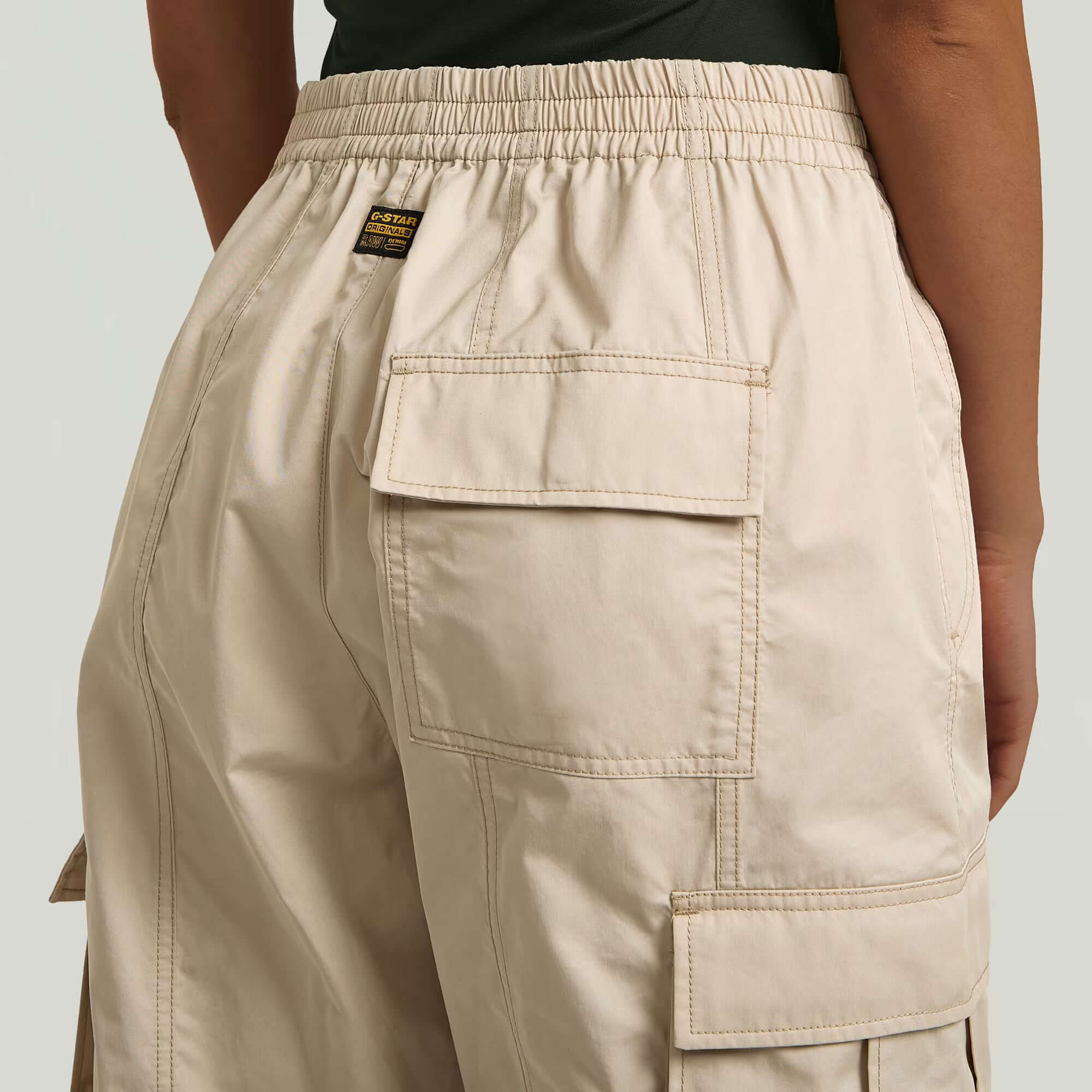 Pantalones Elevated Parachute, vista trasera, detalles de bolsillos y costuras, color beige.