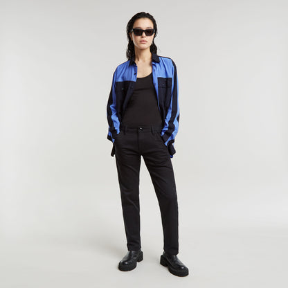 Modelo luciendo pantalones boyfriend Kate con camisa azul y gafas de sol, fondo claro.