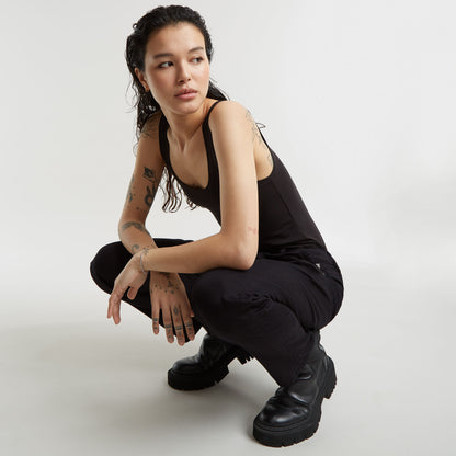Modelo con pantalones boyfriend Kate, camiseta negra y botines oscuros, posando en cuclillas.