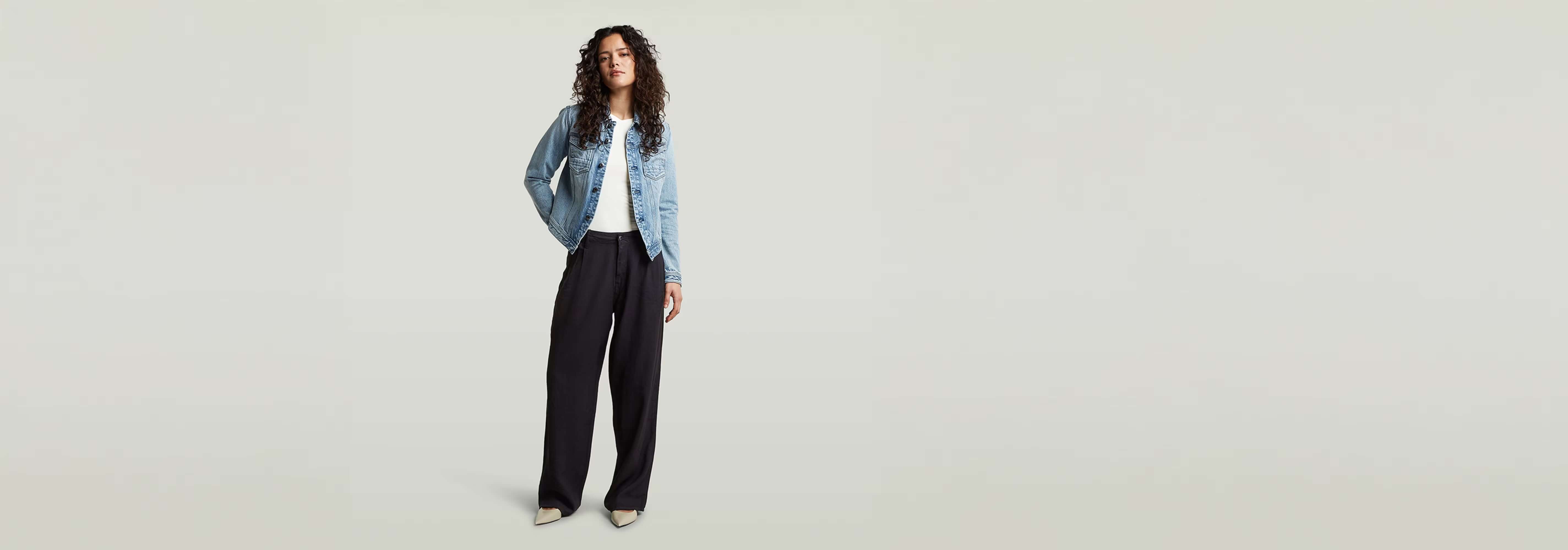 Mujer luciendo pantalones Pleated Chino con chaqueta de mezclilla y camiseta blanca, estilo sofisticado y práctico.