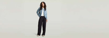 Mujer luciendo pantalones Pleated Chino con chaqueta de mezclilla y camiseta blanca, estilo sofisticado y práctico.