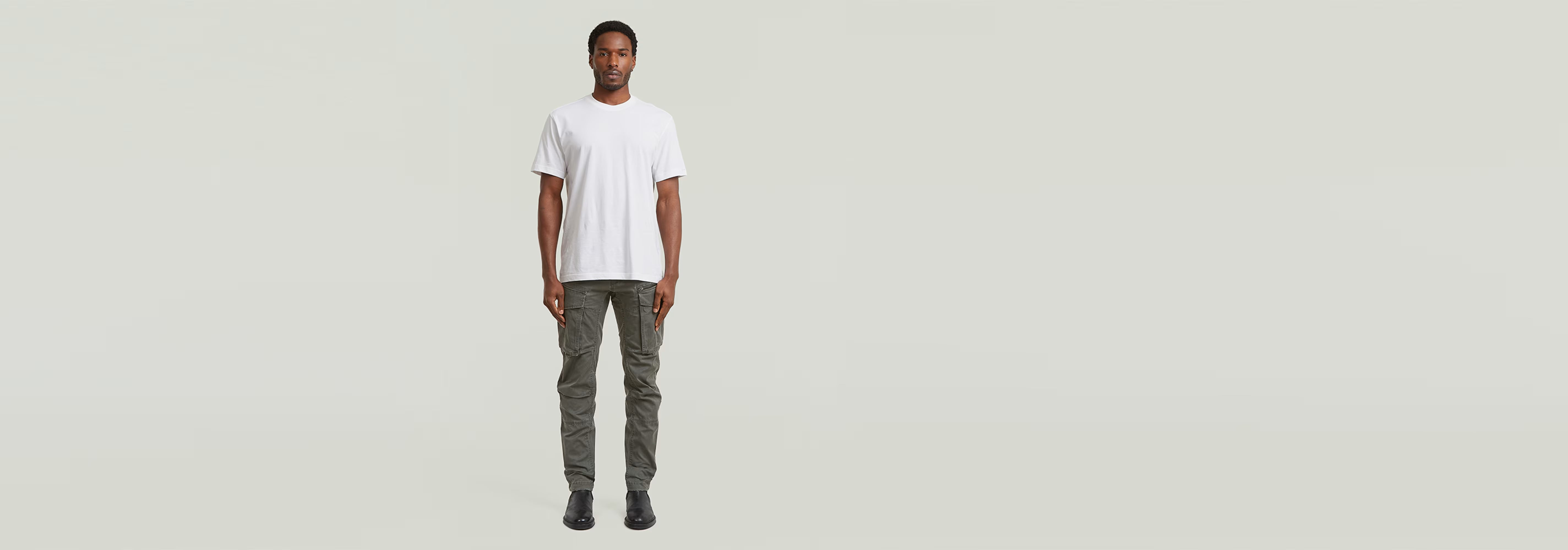 Modelo vistiendo Pantalones Rovic Zip 3D Regular Tapered y camiseta blanca en fondo neutro.