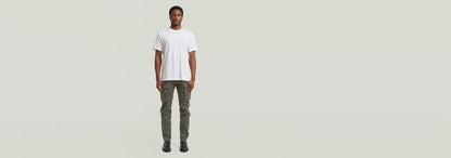 Modelo vistiendo Pantalones Rovic Zip 3D Regular Tapered y camiseta blanca en fondo neutro.