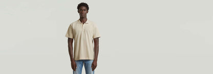Modelo de hombre usando el Polo Core Regular de color beige, con corte regular y cuello de polo.