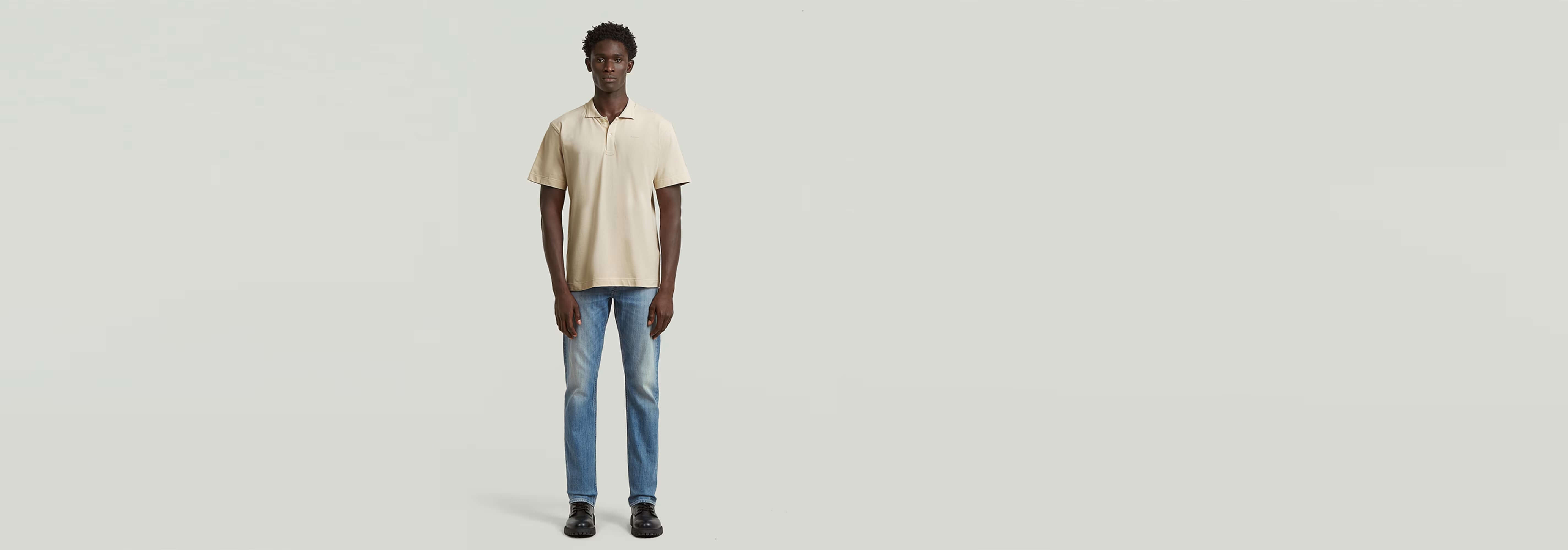 Hombre usando Polo Core Regular Jacquard en color crema con jeans azules, fondo gris claro.