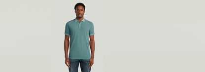 Modelo luciendo la Polo Dunda Overdyed Slim en color verde, con corte ajustado y detalle de cierre de botones.