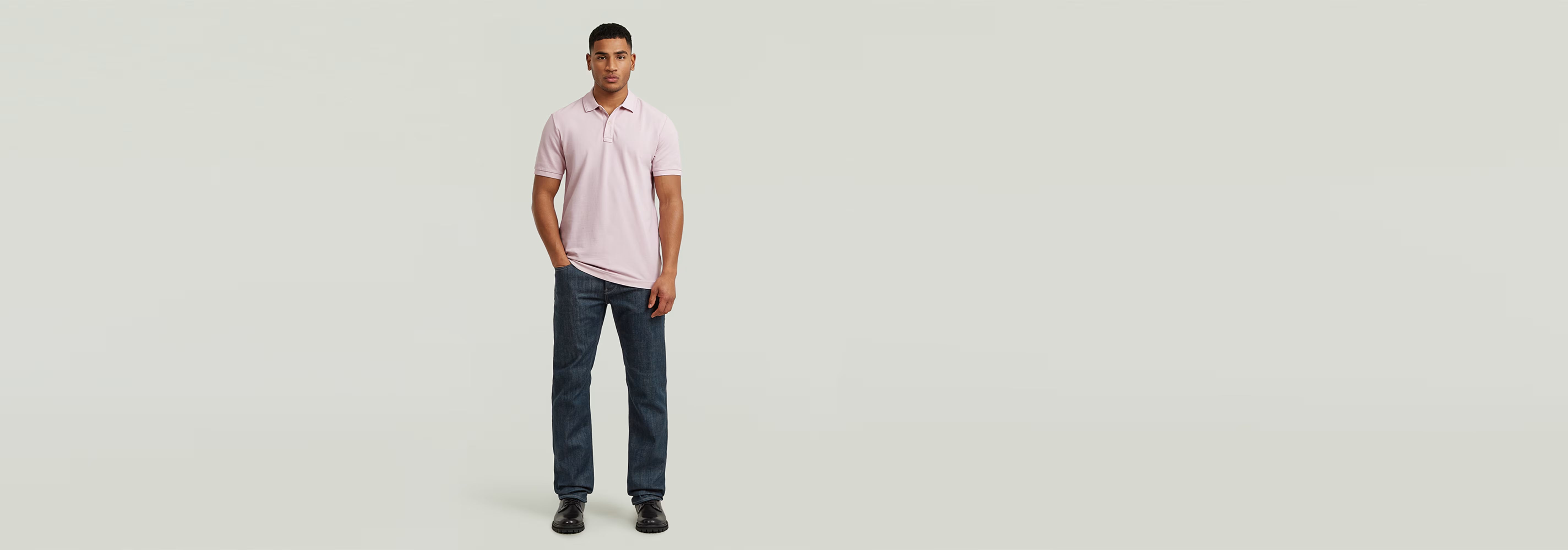 Hombre usando el Polo Dunda Overdyed Slim en color rosa con jeans oscuros en fondo claro.