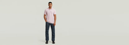Hombre usando el Polo Dunda Overdyed Slim en color rosa con jeans oscuros en fondo claro.