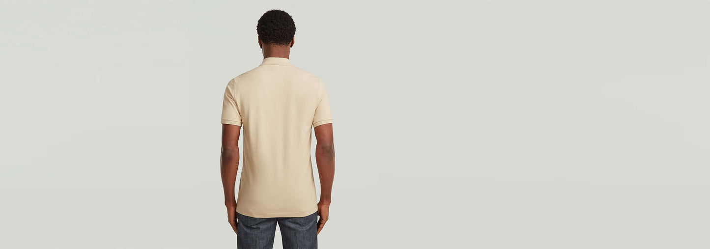 Hombre de espaldas vistiendo el Polo Dunda Slim en color beige.