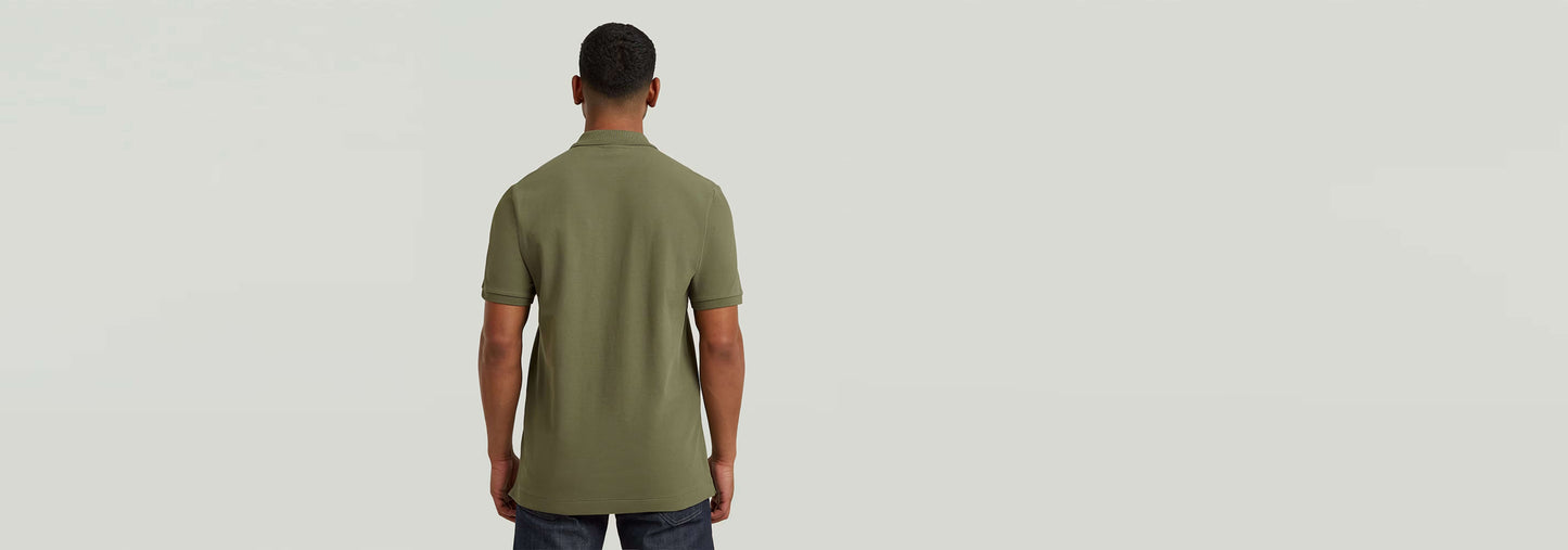 Hombre de espaldas vistiendo el Polo Dunda Slim en color verde olivo con corte ajustado y detalles de diseño.