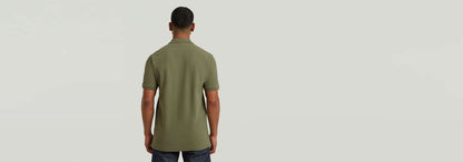 Hombre de espaldas vistiendo el Polo Dunda Slim en color verde olivo con corte ajustado y detalles de diseño.