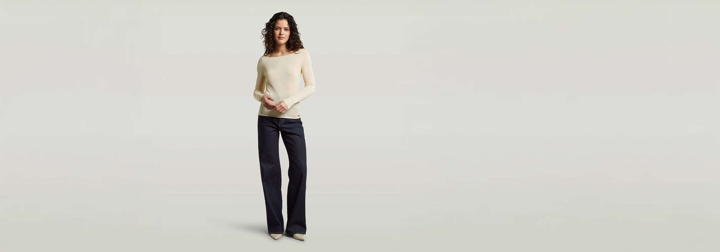 Mujer usando un suéter Punto ajustado Engineered Sheer con jeans, fondo neutro, estilo moderno y elegante.