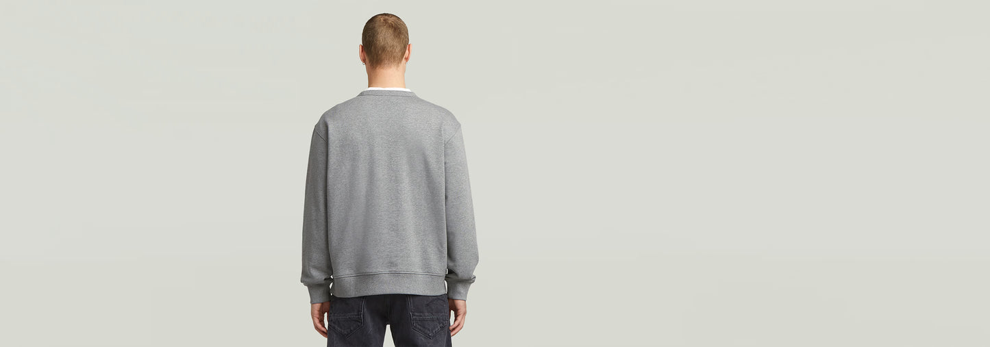 Hombre de espaldas vistiendo una sudadera Applique gris con diseño de corte relajado.