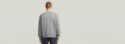 Hombre de espaldas vistiendo una sudadera Applique gris con diseño de corte relajado.