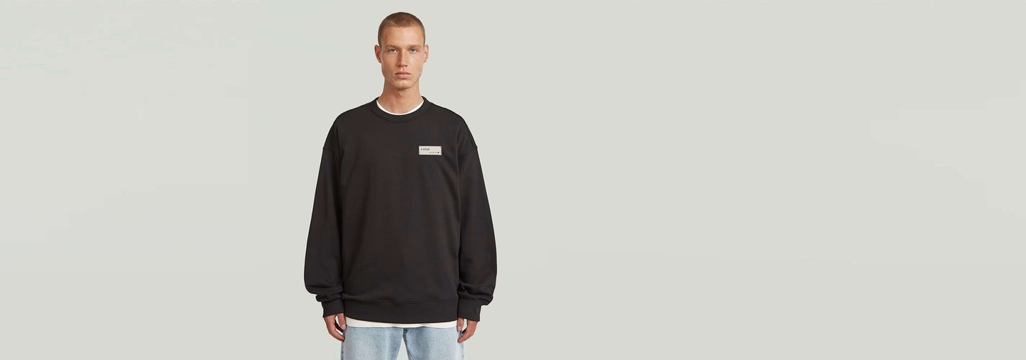 Sudadera HB Badge en color negro con diseño atractivo y corte relajado, ideal para cualquier armario.