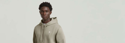 Sudadera Premium Core Hoodie en color verde oliva, con capucha y detalles gráficos sutiles.