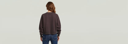 Modelo de espaldas luciendo el suéter Washed Loose V de corte extragrande, cómodo y de algodón ecológico.