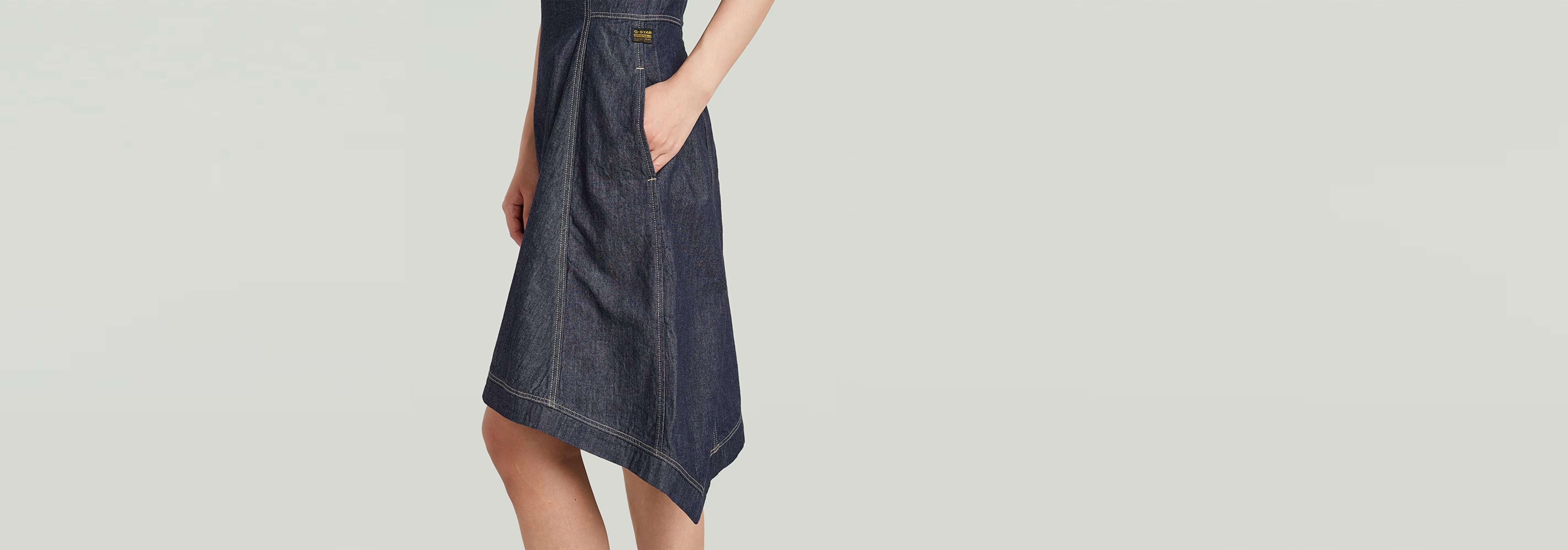 Vestido Short Flared en denim oscuro con diseño acampanado y bolsillos laterales.