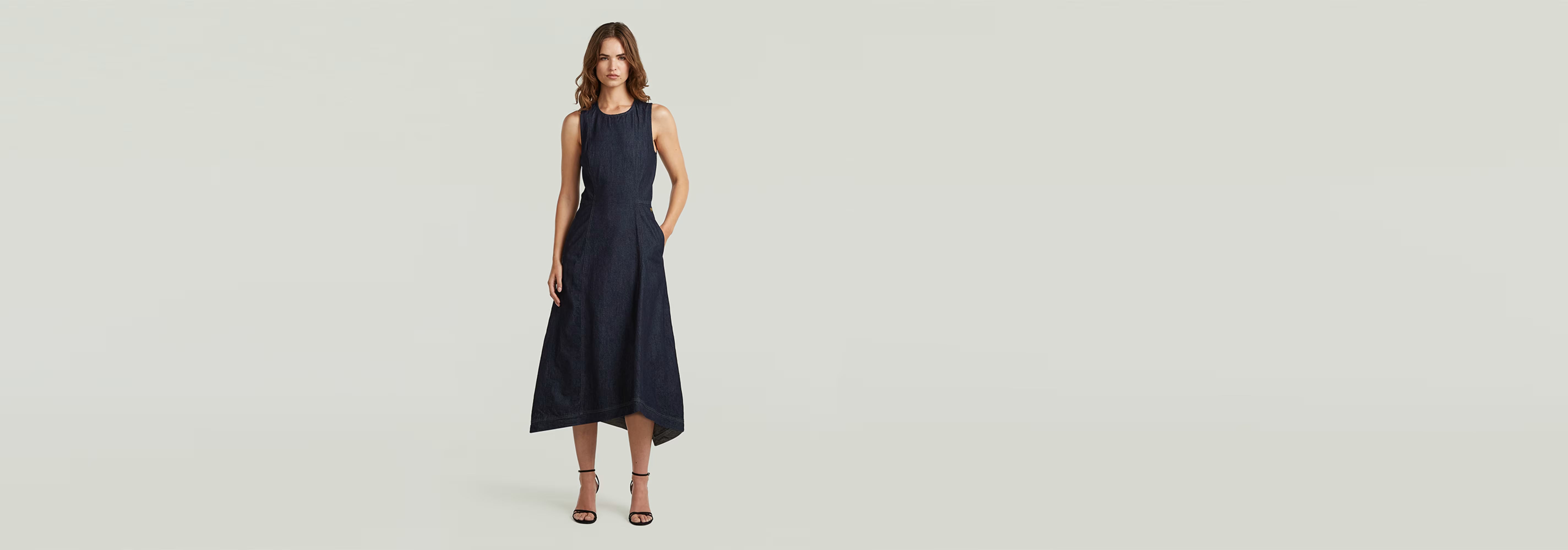 Modelo usando un vestido Vaquero Core Flare, corte superslim y elegante con tirantes anchos.